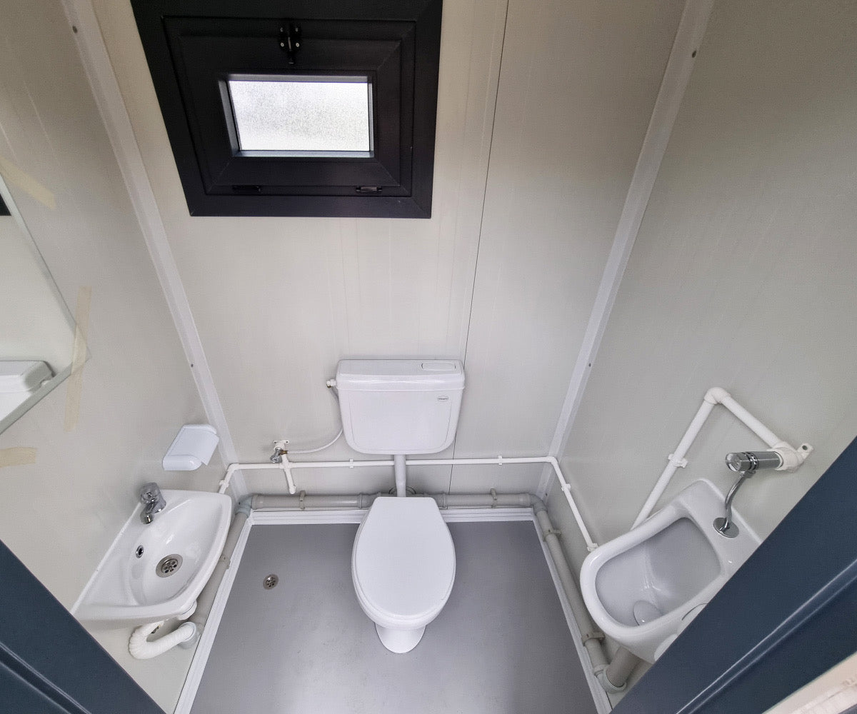 Contentor sanitário novo de formato compacto, equipado com sanita, urinol e lavatório.