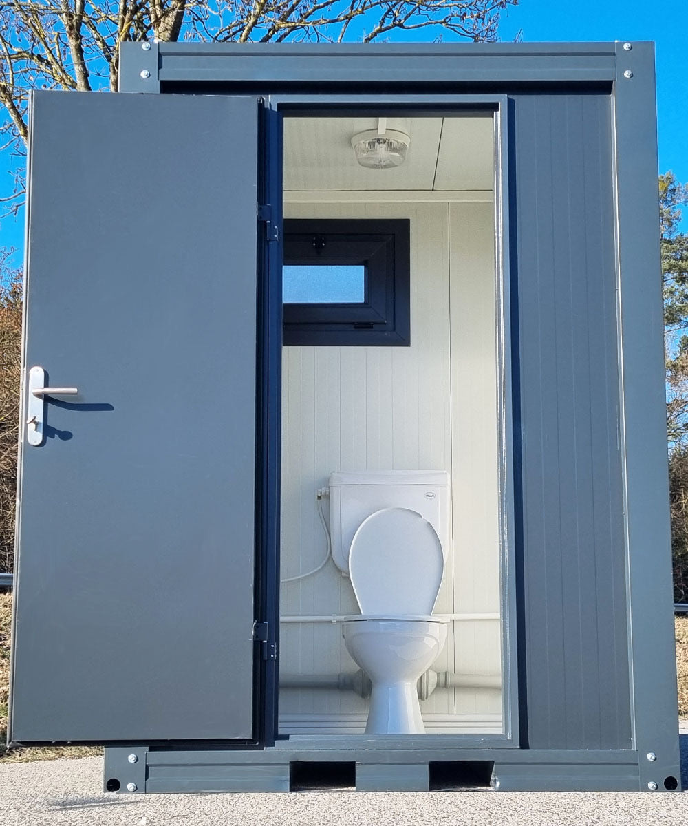 Contentor sanitário novo de formato compacto, equipado com sanita, urinol e lavatório.